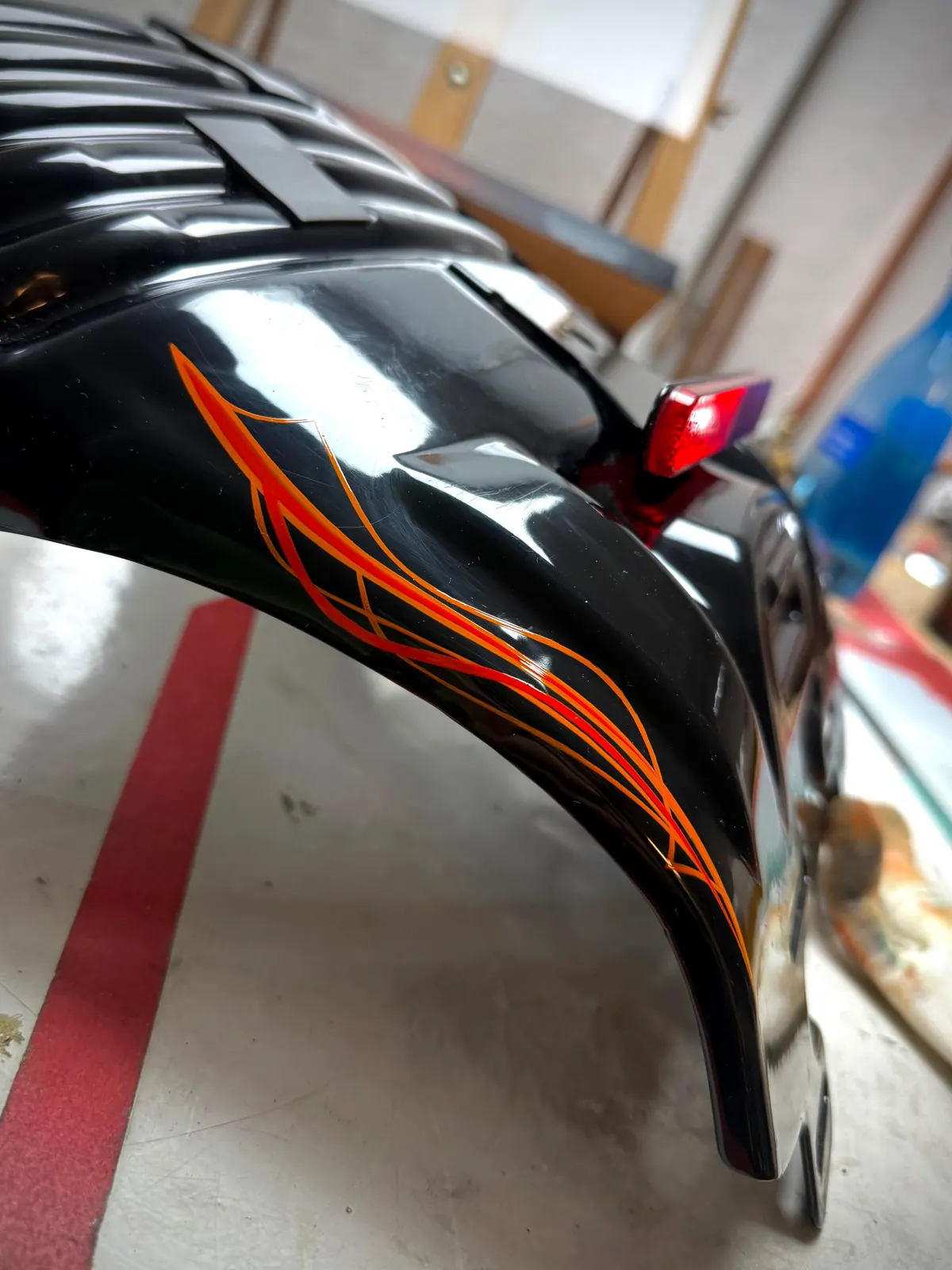 Orangefarbenes Pinstriping auf einem Motorradteil