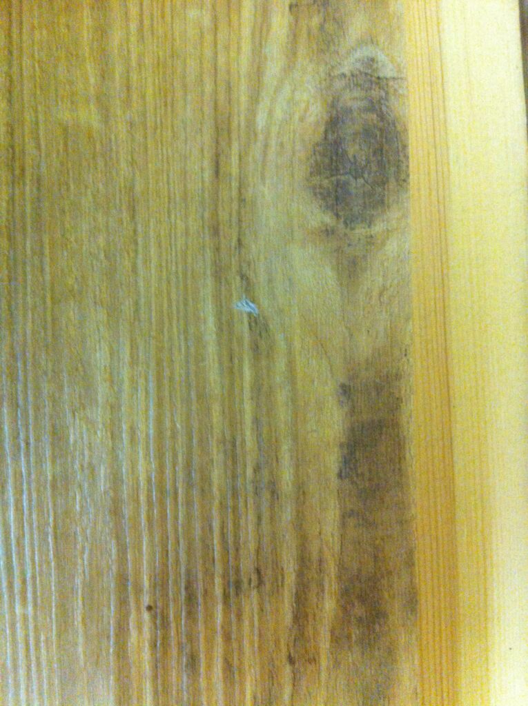 Kleine helle Schadstelle an einer Fußbodenplatte in Holzoptik vor der Reparatur